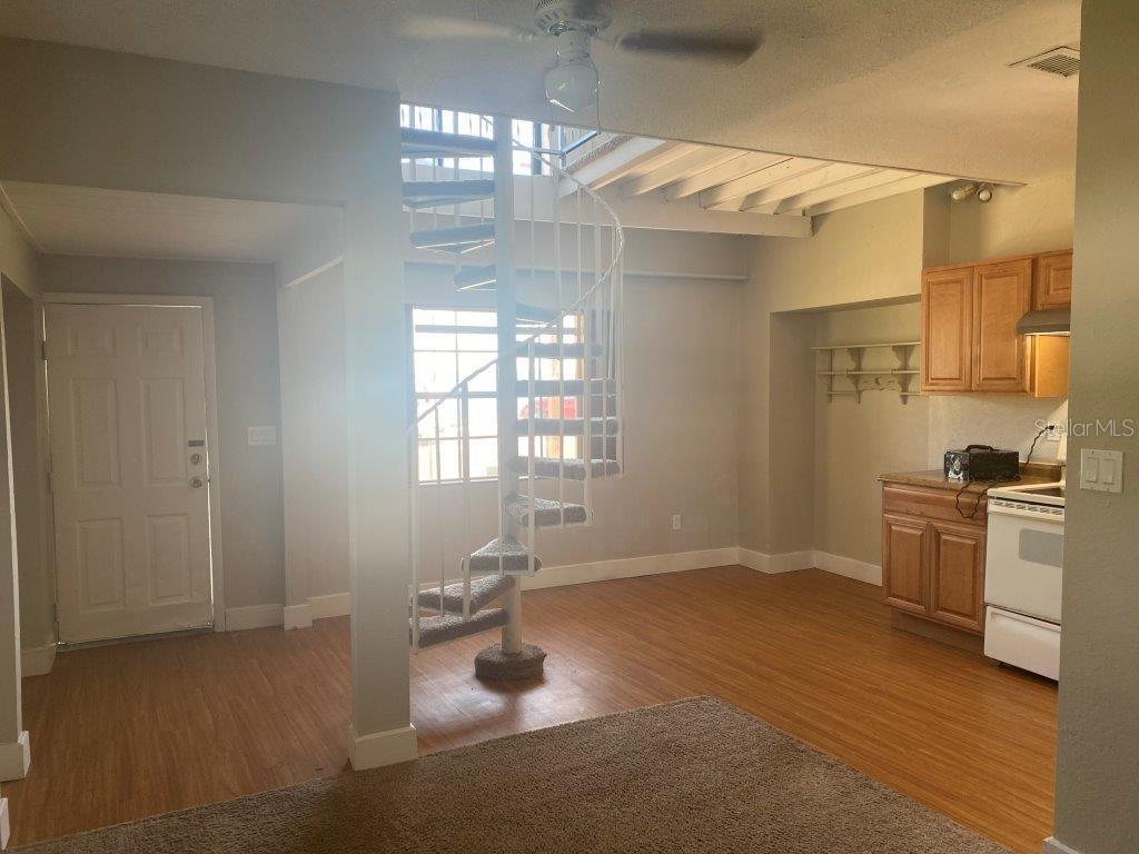 An interior view shows a kitchen area with wooden cabinets and a spiral staircase — 741 W OSCEOLA STREET, CLERMONT, FL