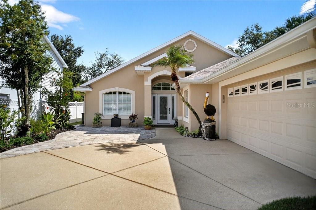 A tan single-story house features a paved walkway, a two-car garage, and a pelican statue — 83 COVINGTON LANE, PALM COAST, FL