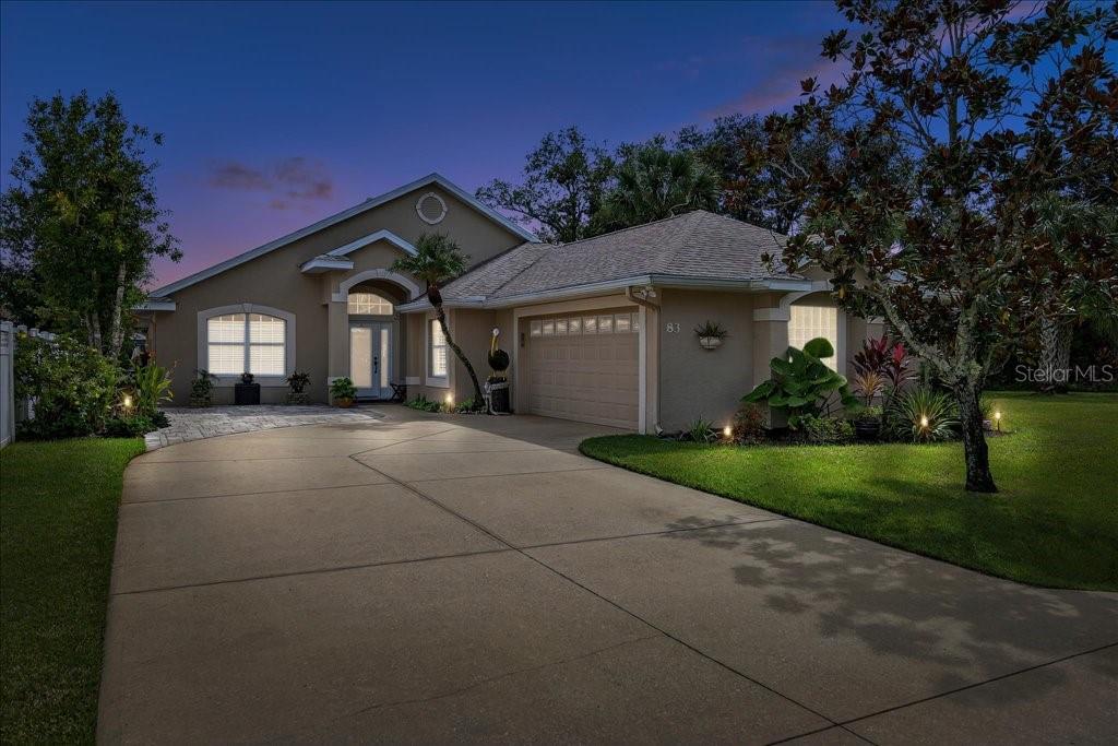 A single-story house with a beige stucco exterior, a two-car garage, and a concrete driveway — 83 COVINGTON LANE, PALM COAST, FL