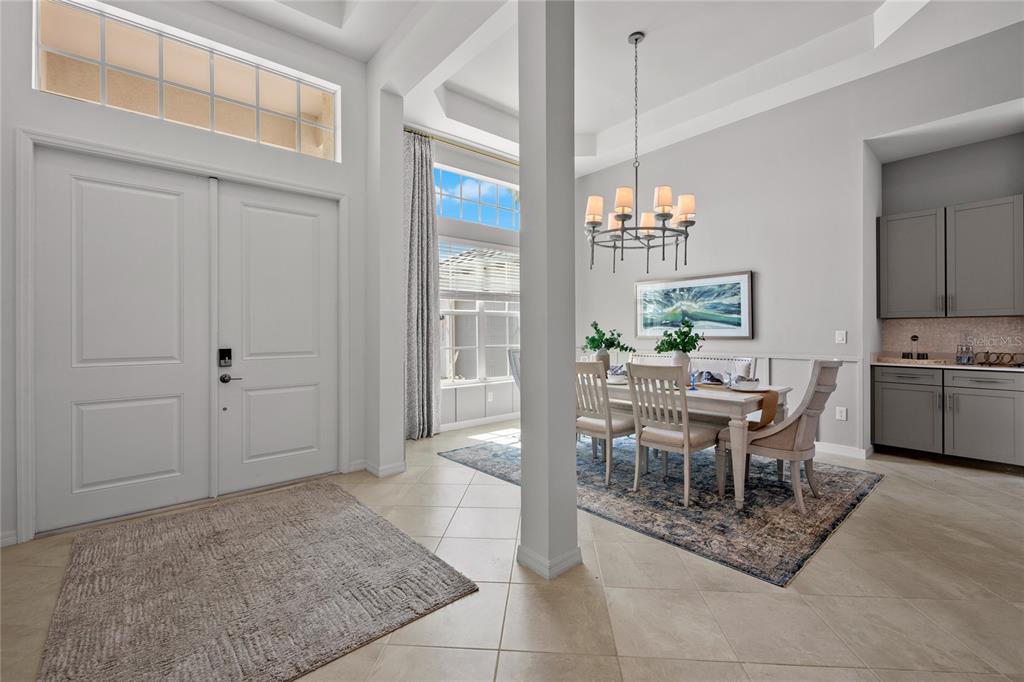 A dining area with a chandelier, table, and chairs sits adjacent to an entryway — 18923 CHERRYSTONE WAY, LAKEWOOD RANCH, FL