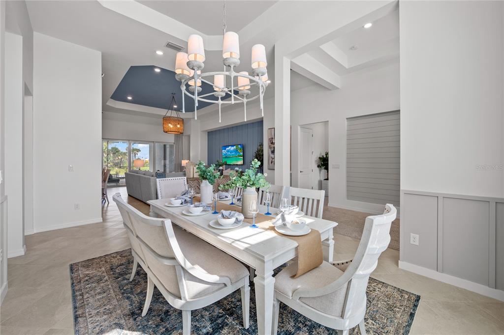 A dining room features a white table, upholstered chairs, a chandelier, and blue accent walls — 18923 CHERRYSTONE WAY, LAKEWOOD RANCH, FL