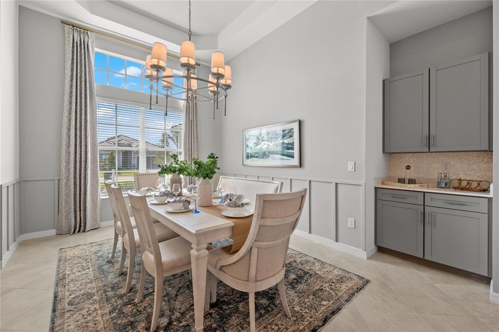 A dining room features a chandelier, a table with six chairs, and gray built-in cabinets — 18923 CHERRYSTONE WAY, LAKEWOOD RANCH, FL