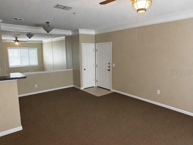 An interior view of a room with brown carpet, beige walls, and a mirrored wall section — 4802 51ST STREET W UNIT 1805, BRADENTON, FL