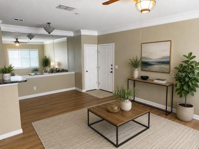 A living room features wood-look flooring, a coffee table, a console table, and mirrored walls — 4802 51ST STREET W UNIT 1805, BRADENTON, FL