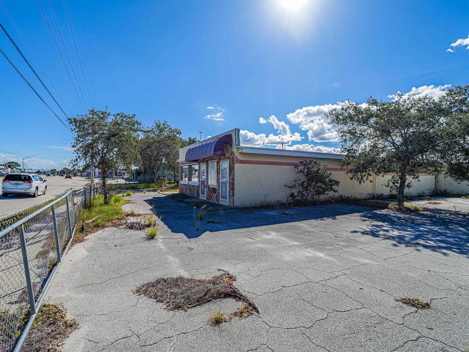 A single-story commercial building with a purple awning sits on a cracked asphalt lot — 2814 S Harbor City Boulevard, Melbourne FL 32901, MELBOURNE, FL