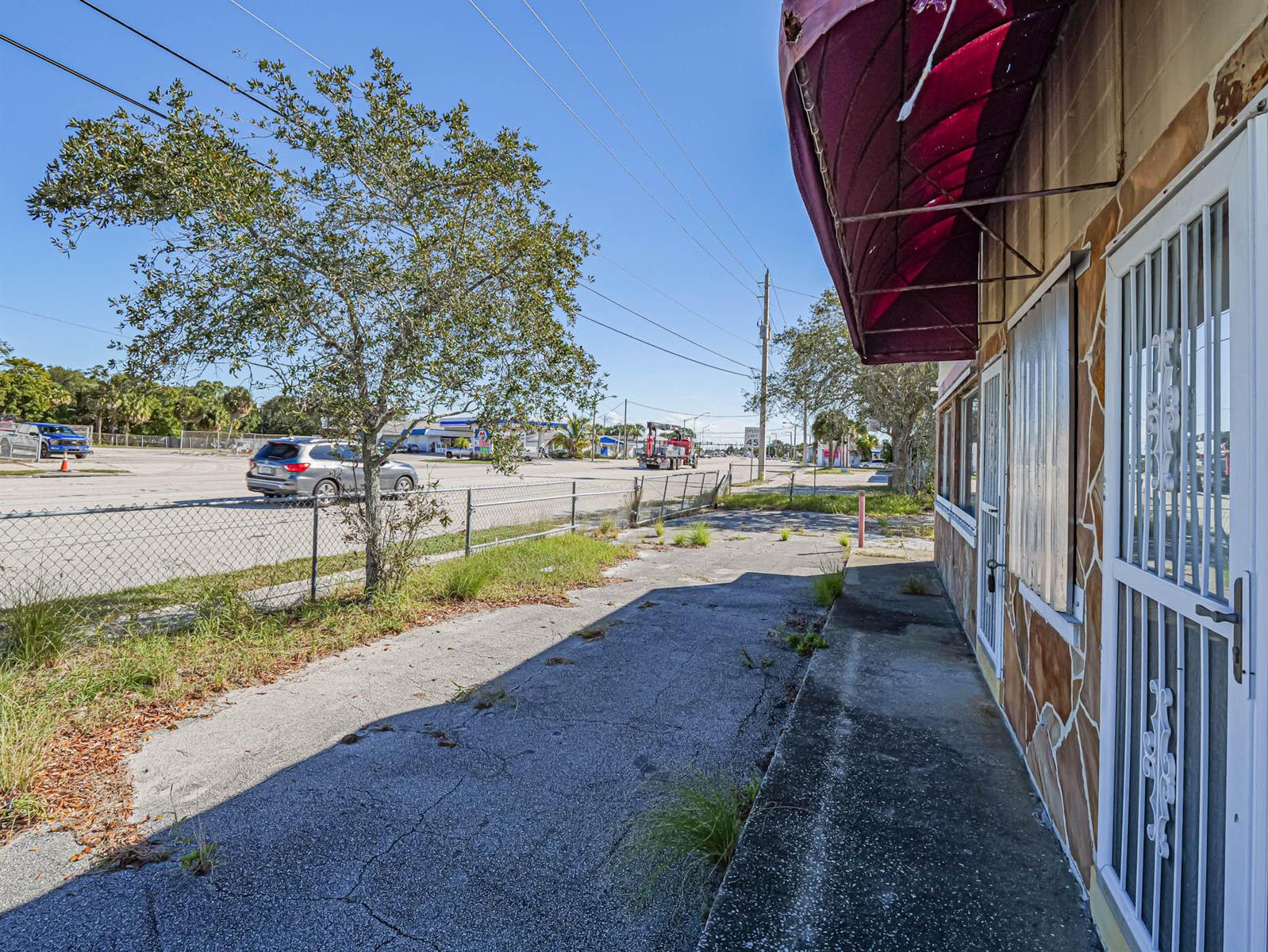 A view of a building exterior with a red awning, metal security doors, and sidewalk — 2814 S Harbor City Boulevard, Melbourne FL 32901, MELBOURNE, FL