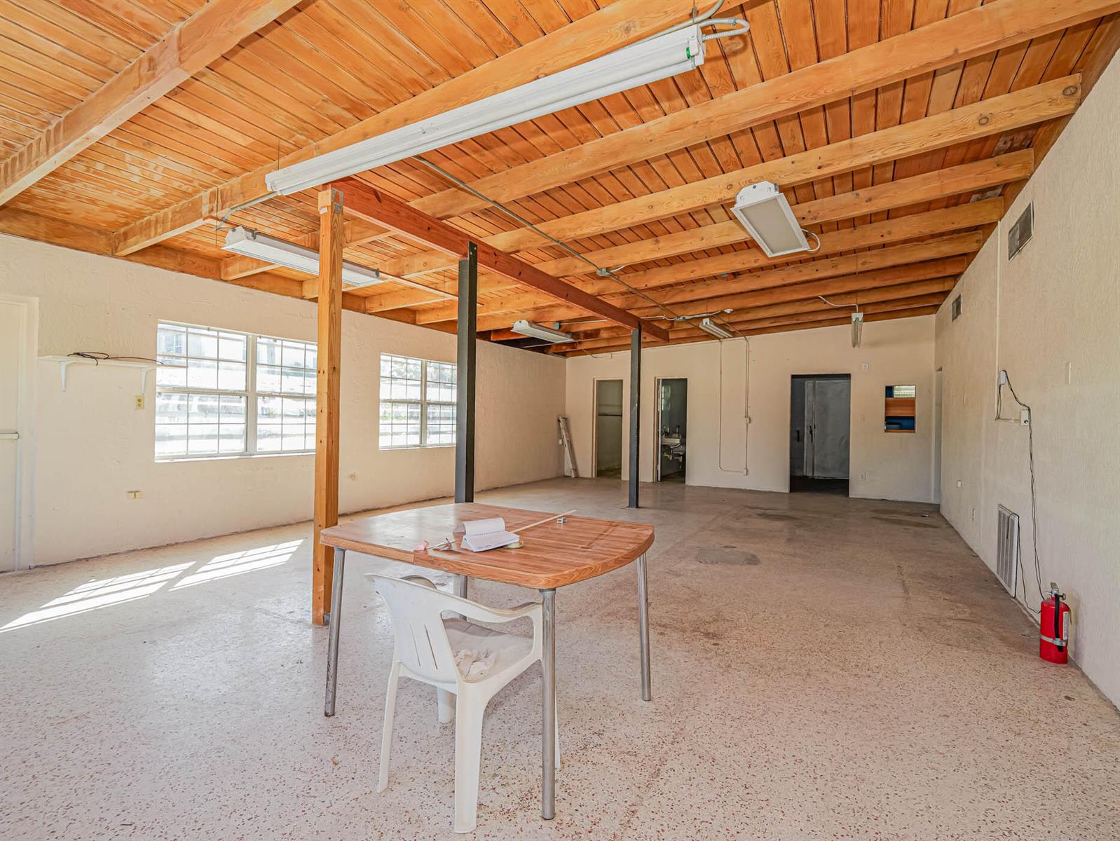 An open commercial space features a wooden beamed ceiling, concrete floors, and a central table — 2814 S Harbor City Boulevard, Melbourne FL 32901, MELBOURNE, FL