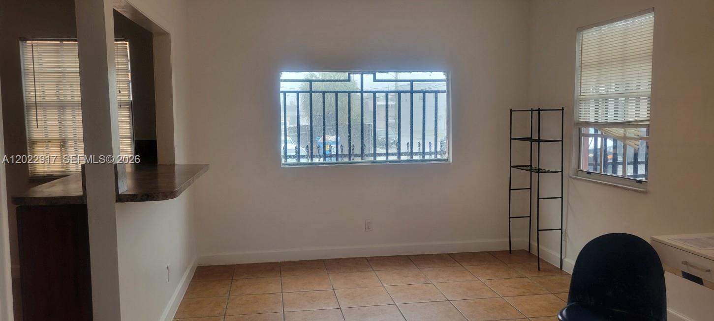A room with tiled floors, a breakfast bar, a window with security bars, and shelving — 71 NW 18th Ave, Miami FL 33125, MIAMI, FL