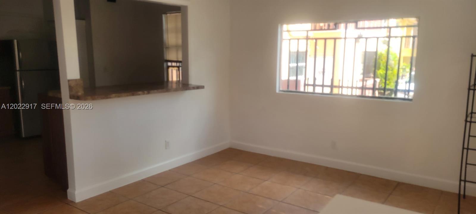 An interior view of a room with tiled floors, a breakfast bar, and a window — 71 NW 18th Ave, Miami FL 33125, MIAMI, FL