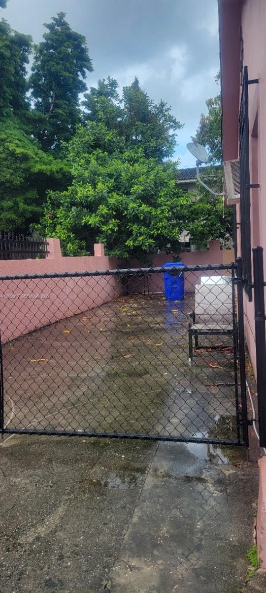A fenced-in concrete patio area features a blue trash bin and a single chair — 71 NW 18th Ave, Miami FL 33125, MIAMI, FL