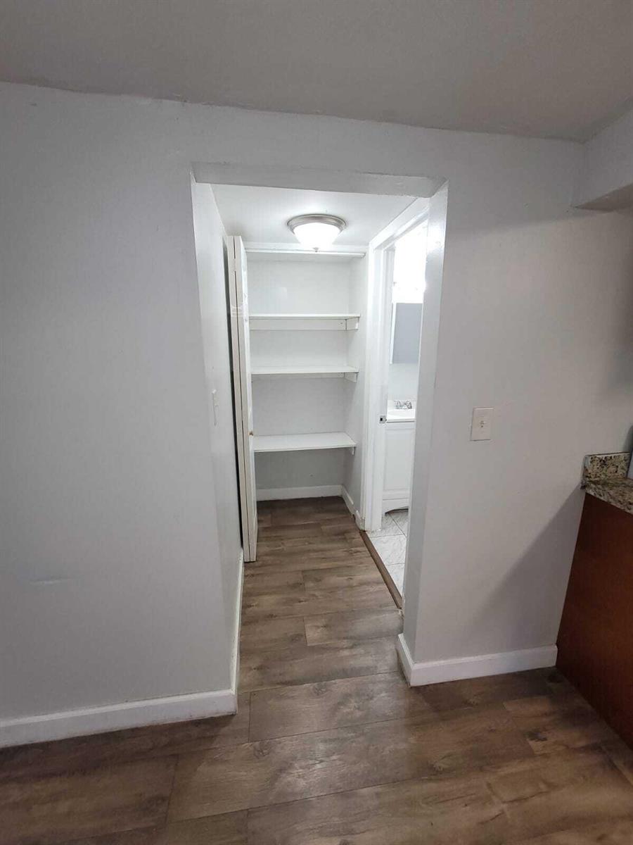 A hallway leads to a walk-in storage closet with white shelves and wood-look flooring — 210 SW 7th Street, Dania Beach FL 33004, DANIA BEACH, FL