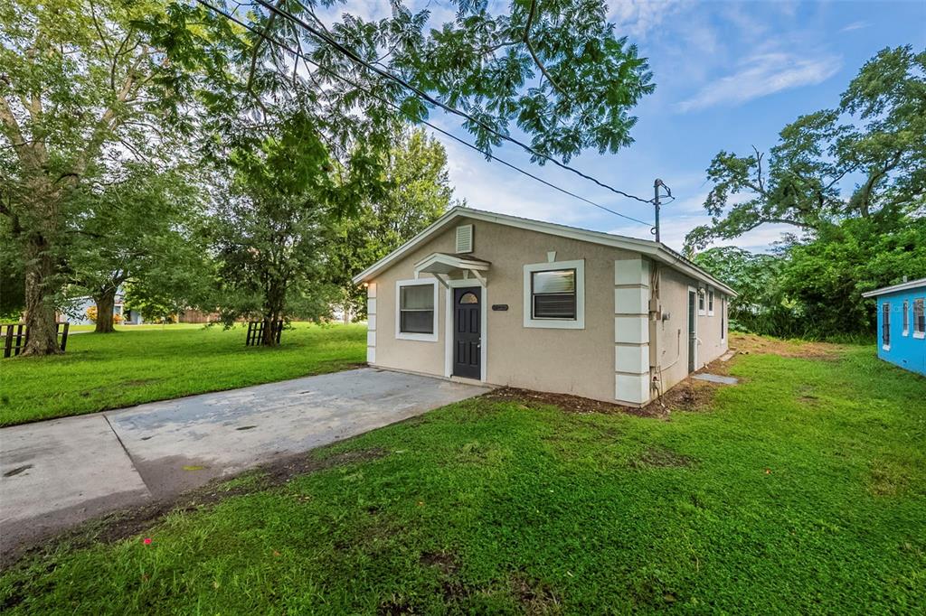 A single-story tan house with a concrete driveway, a dark front door, and green lawn — 523 CARVER BOULEVARD, ORLANDO, FL