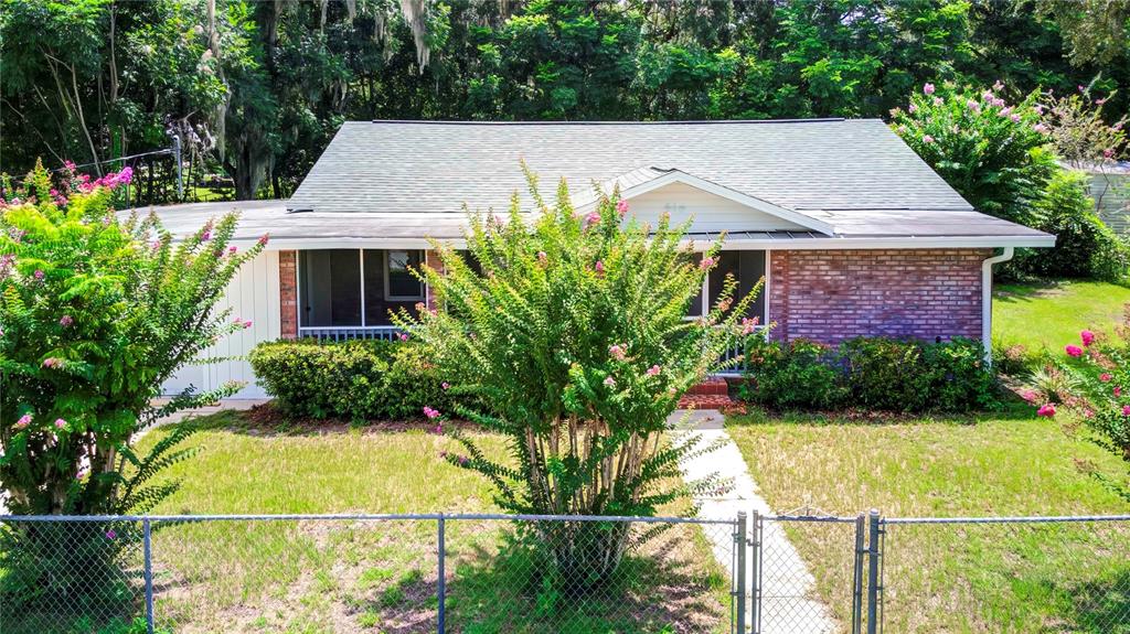 A single-story brick house with a gabled roof and a chain-link fence in front — 614 POWELL STREET, WILDWOOD, FL