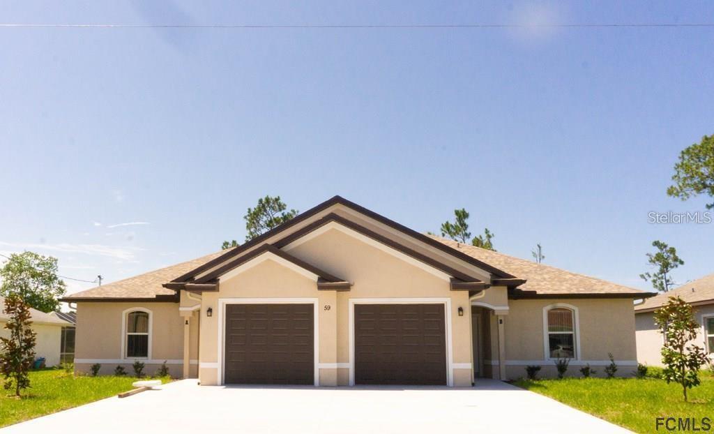 A single-story duplex with two garage doors and light-colored stucco exterior under a clear sky — 59 FANSHAWE LANE UNIT B, PALM COAST, FL