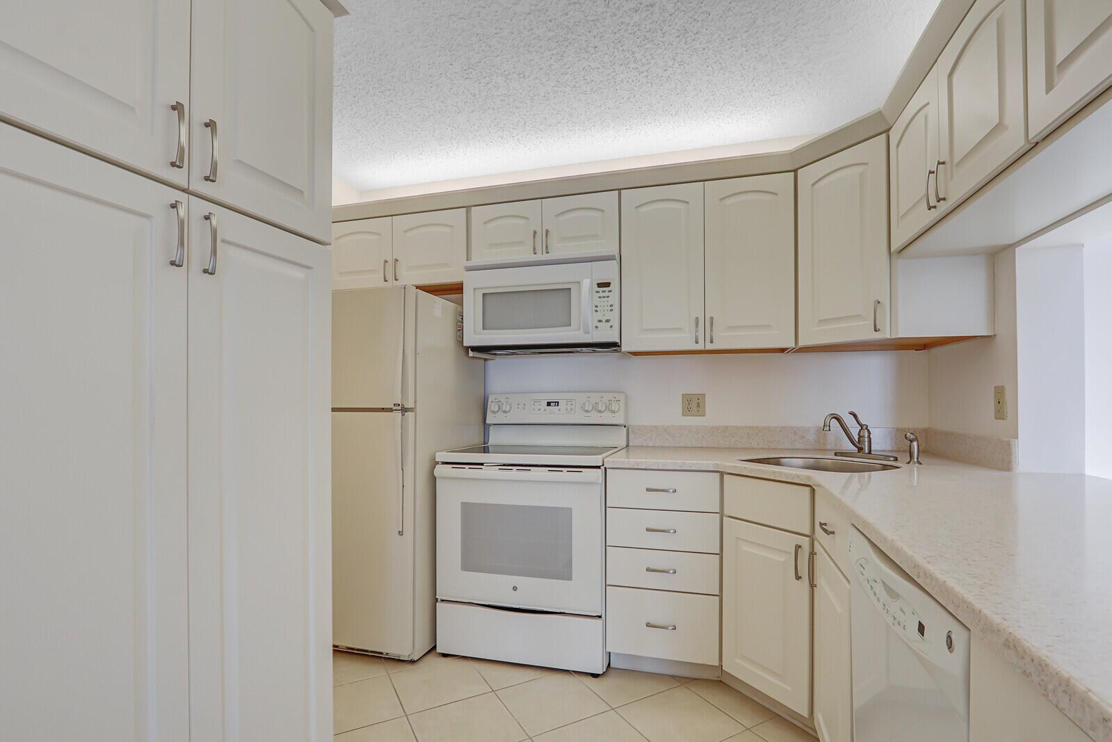 A kitchen with white cabinets, white appliances, and light-colored countertops on a tiled floor — 4468 NE Ocean Boulevard # 3, Jensen Beach FL 34957, JENSEN BEACH, FL