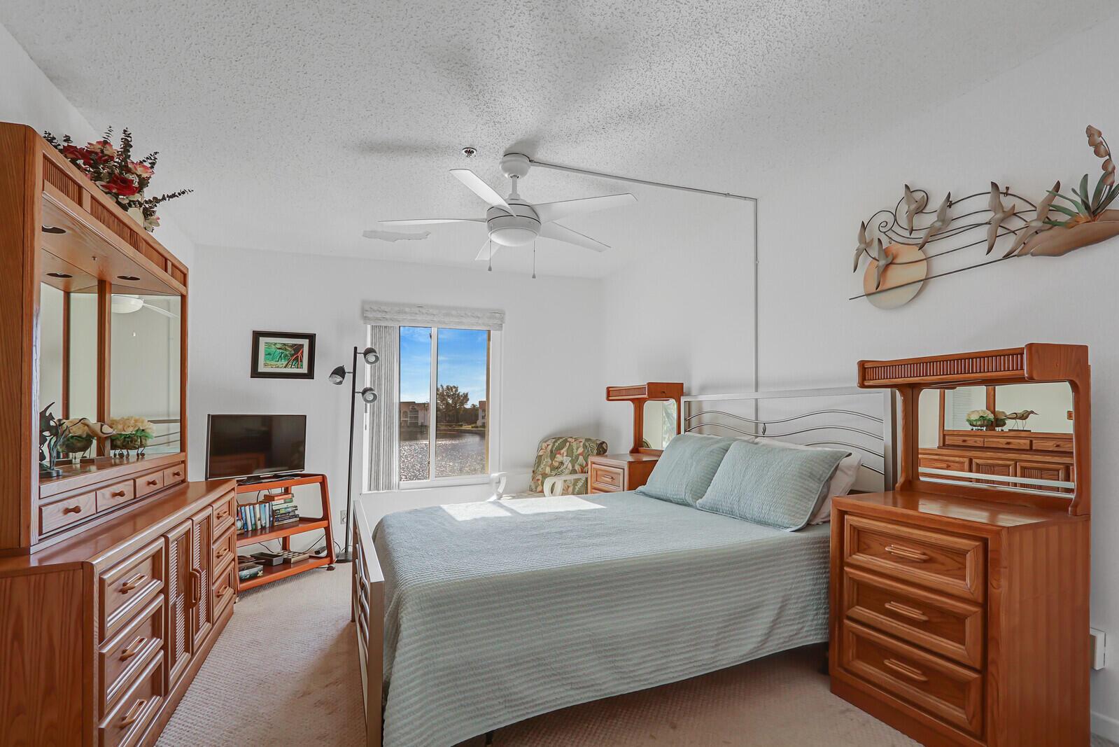 A bedroom with a bed, wooden furniture, a ceiling fan, and a window overlooking water — 4468 NE Ocean Boulevard # 3, Jensen Beach FL 34957, JENSEN BEACH, FL