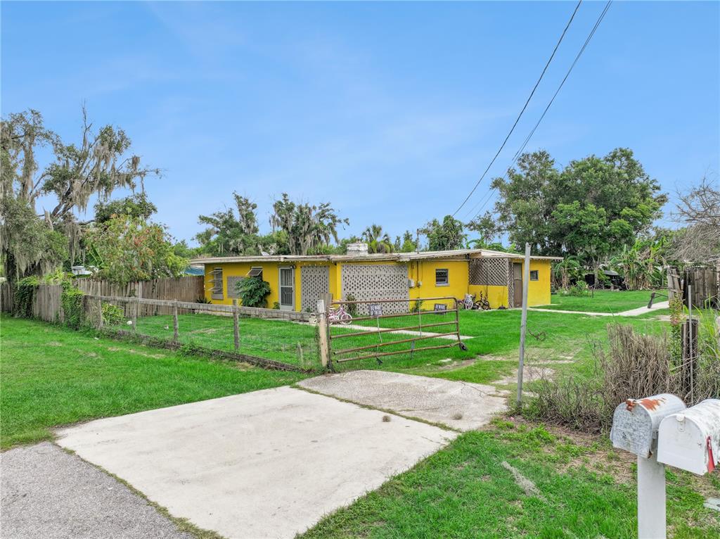 A yellow single-story house with a fenced yard and a concrete driveway — 825 COOK ROAD, MULBERRY, FL