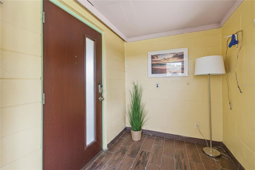 An entryway features yellow block walls, a brown door with a window, and tile flooring — 825 COOK ROAD, MULBERRY, FL