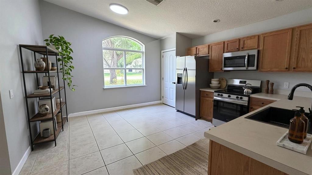 A kitchen with wood cabinets, stainless steel appliances, and a dining area with a window — 649 MACON DRIVE, TITUSVILLE, FL