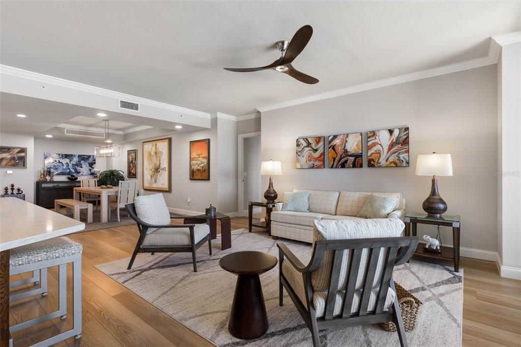 A living room with a ceiling fan, patterned rug, sofa, two armchairs, and dining area — 19 AVENUE DE LA MER UNIT 502, PALM COAST, FL