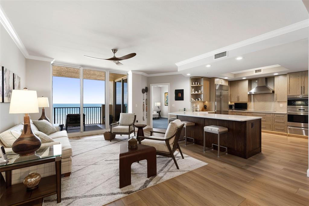 An open-concept living room and kitchen with ocean views, light wood floors, and modern furniture — 19 AVENUE DE LA MER UNIT 502, PALM COAST, FL