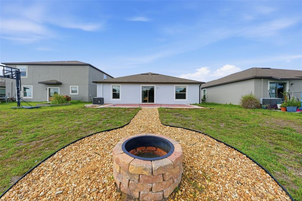 The backyard features a stone fire pit, a gravel path, and a concrete patio — 16638 DELIA STREET, WIMAUMA, FL