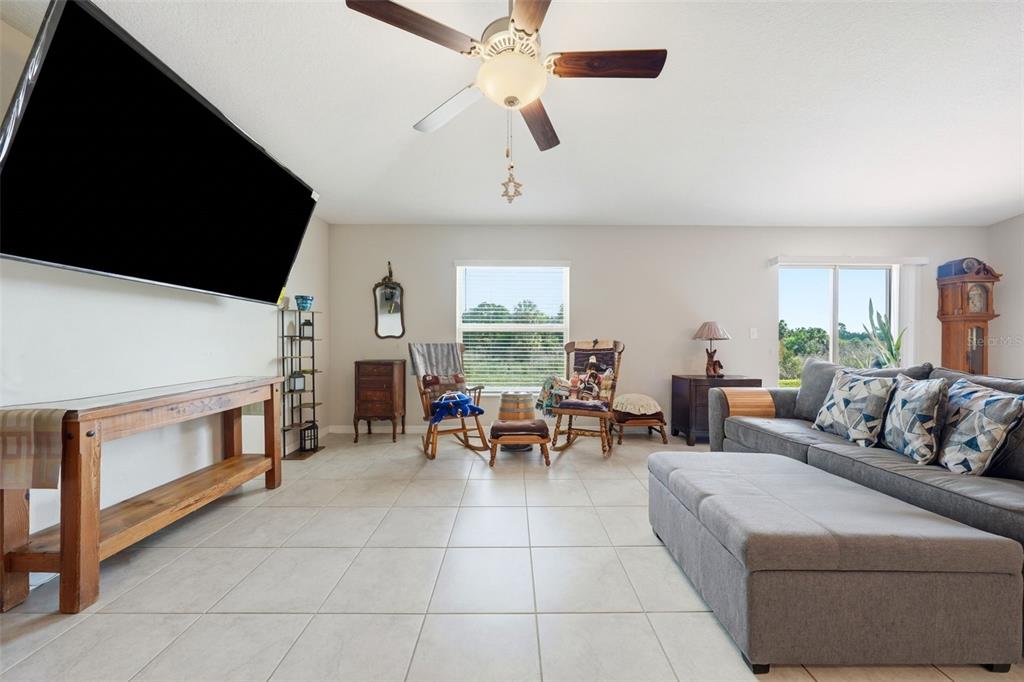 A living room features light tile floors, a ceiling fan, and a large wall-mounted television — 16638 DELIA STREET, WIMAUMA, FL