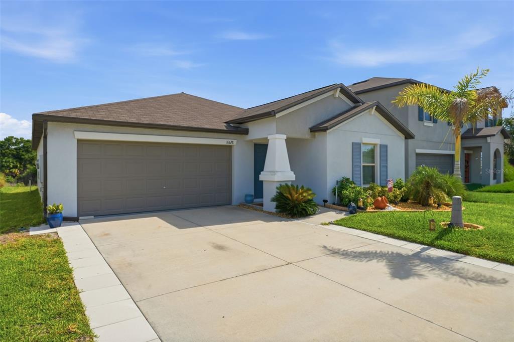 A single-story suburban house with a two-car garage, gray stucco exterior, and a concrete driveway — 16638 DELIA STREET, WIMAUMA, FL