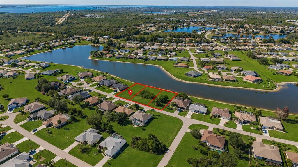An aerial view shows three adjacent vacant residential lots bordering a lake in a neighborhood — 2377 SOFIA LANE, PUNTA GORDA, FL