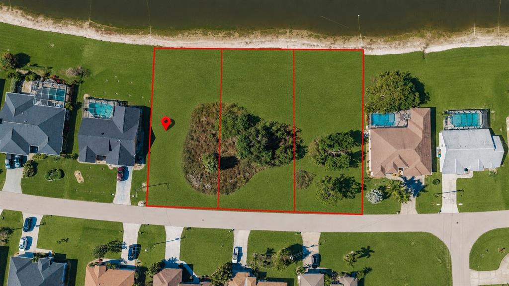 An aerial view shows three adjacent vacant residential lots bordering a lake — 2377 SOFIA LANE, PUNTA GORDA, FL