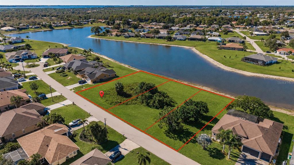 An aerial view shows three adjacent vacant residential lots bordering a lake in a neighborhood — 2377 SOFIA LANE, PUNTA GORDA, FL