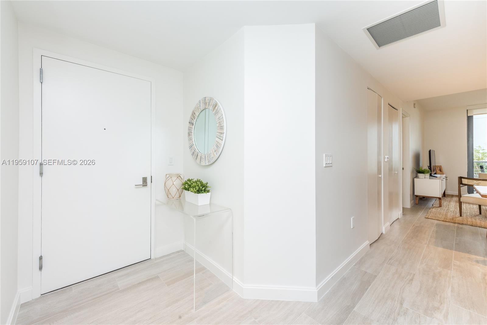 An entryway features a white door, a clear console table, and light wood-look flooring — 55 SW 9th St # 1010, Miami FL 33130, MIAMI, FL