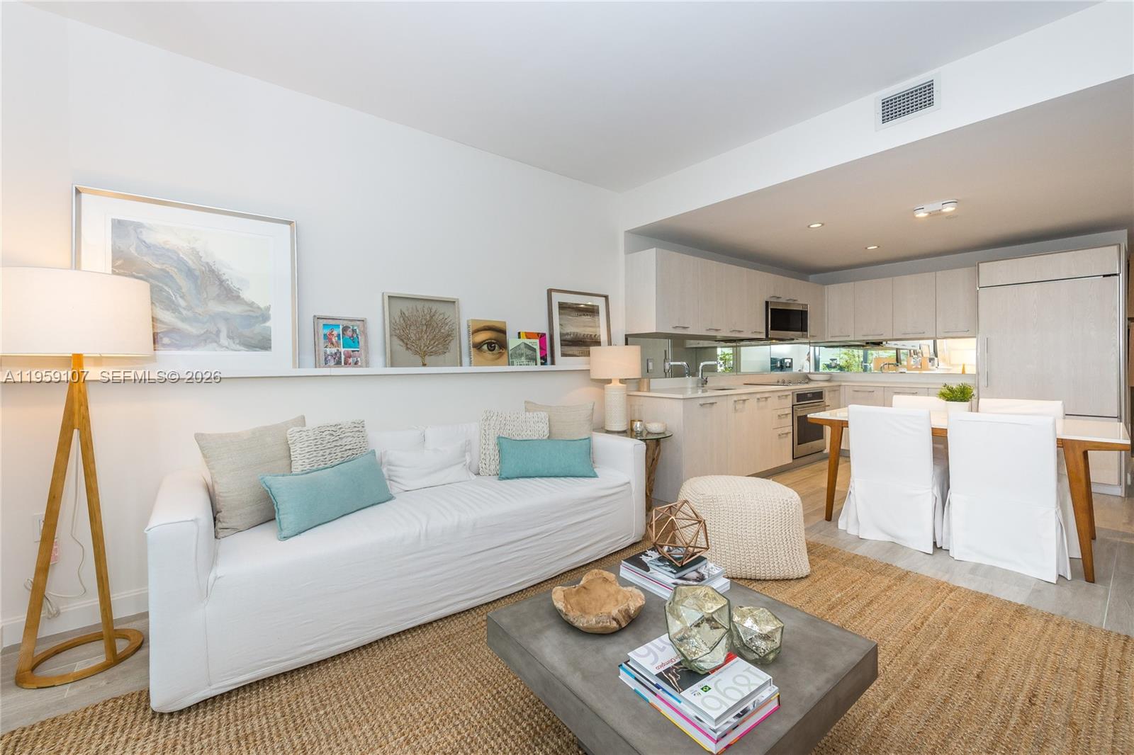 A living room with a white sofa and a kitchen with light wood cabinets — 55 SW 9th St # 1010, Miami FL 33130, MIAMI, FL