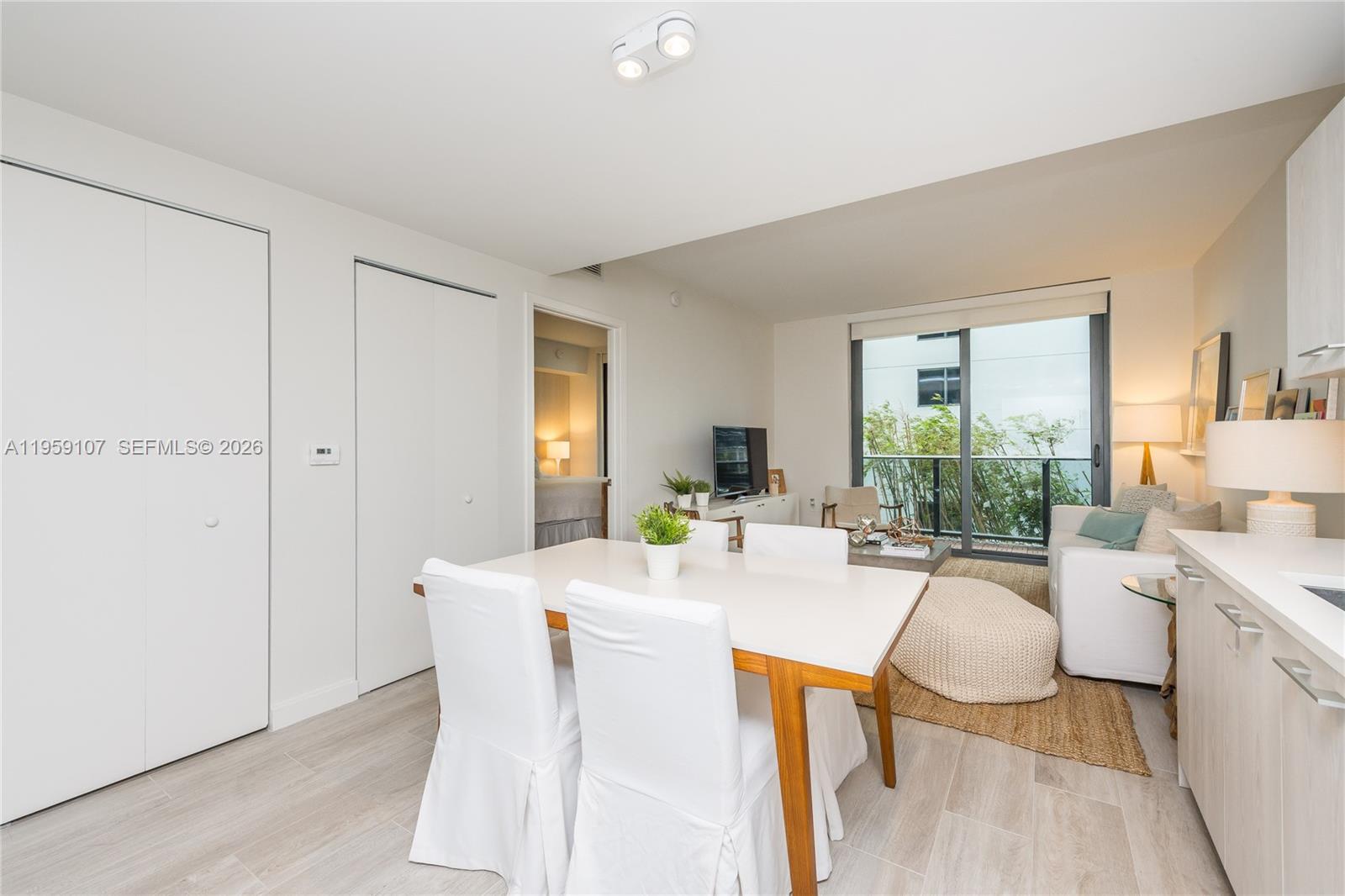 A bright living and dining area features white furniture, light wood flooring, and a balcony — 55 SW 9th St # 1010, Miami FL 33130, MIAMI, FL