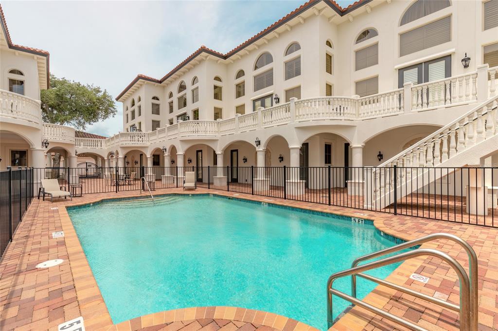 A large swimming pool sits in the courtyard of a multi-story white Mediterranean-style building — 5090 RIVERSIDE DRIVE UNIT 103, PORT ORANGE, FL