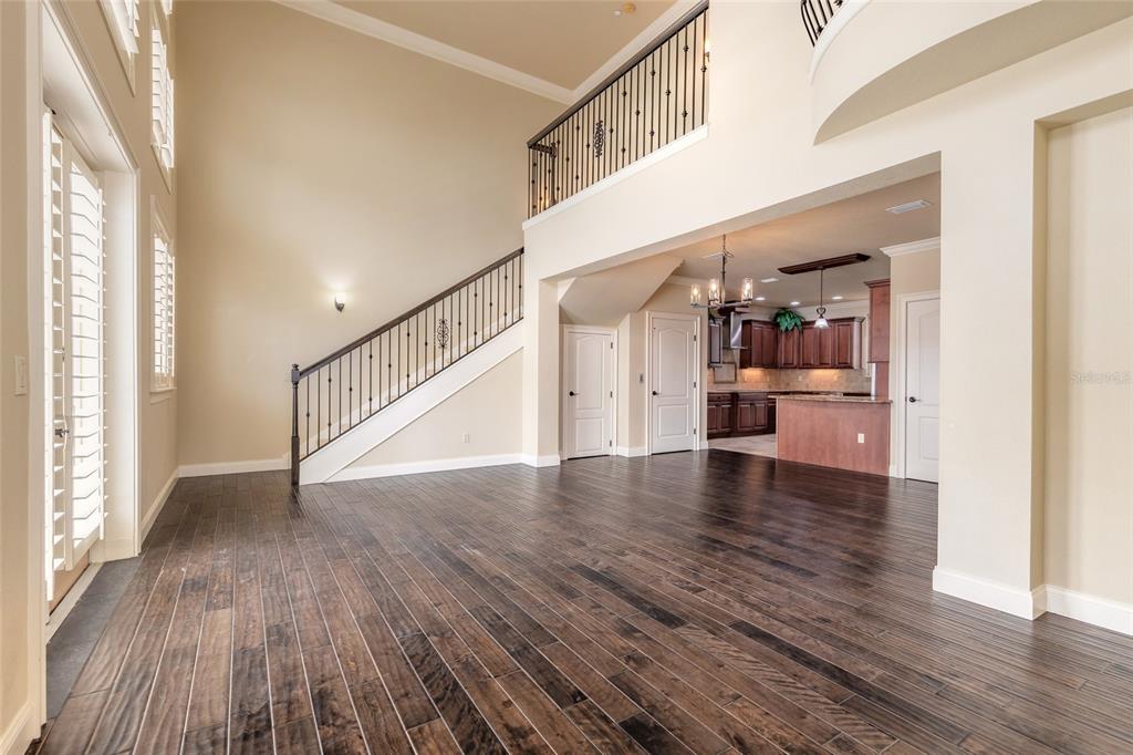 A spacious living area features dark wood flooring, a staircase with iron railings, and an open kitchen — 5090 RIVERSIDE DRIVE UNIT 103, PORT ORANGE, FL