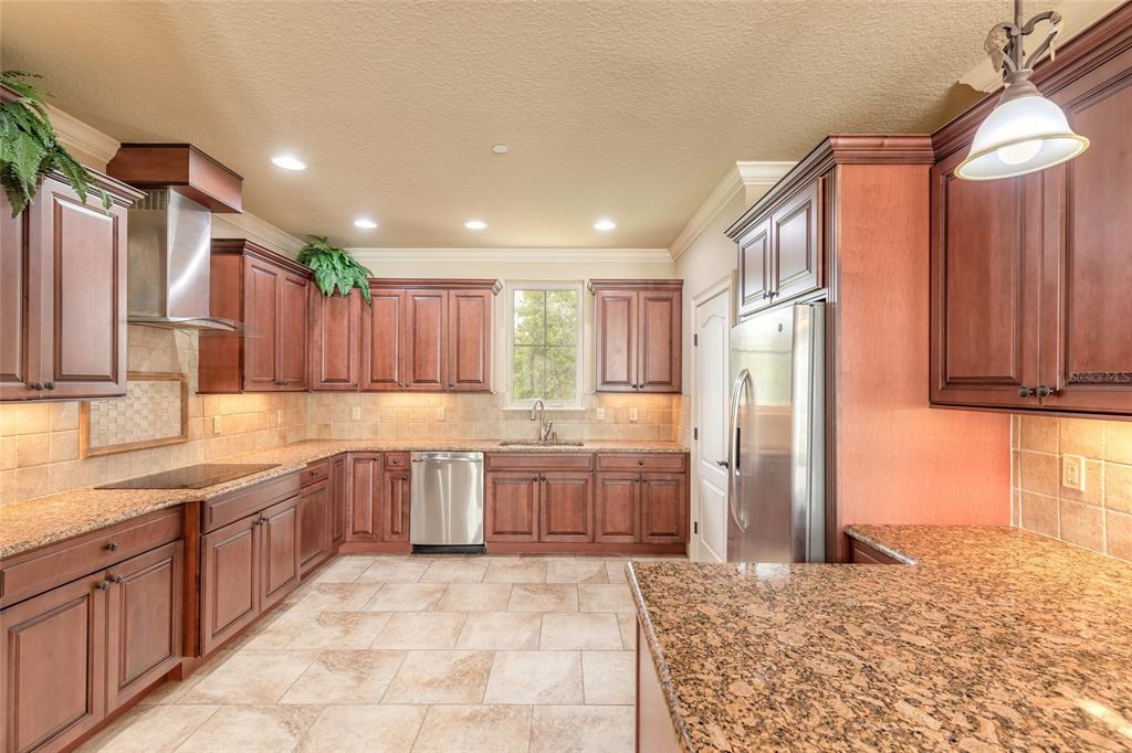 A kitchen with dark wood cabinets, granite countertops, stainless steel appliances, and tile flooring — 5090 RIVERSIDE DRIVE UNIT 103, PORT ORANGE, FL