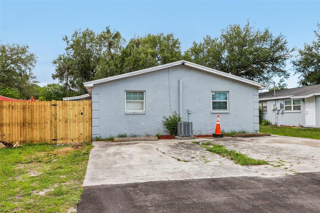A light blue single-story house exterior features a concrete driveway and a wooden privacy fence — 3780 137TH AVENUE, LARGO, FL