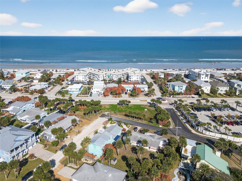 An aerial view shows a coastal neighborhood with houses, palm trees, and a beach — 923 LOCUST STREET, NEW SMYRNA BEACH, FL