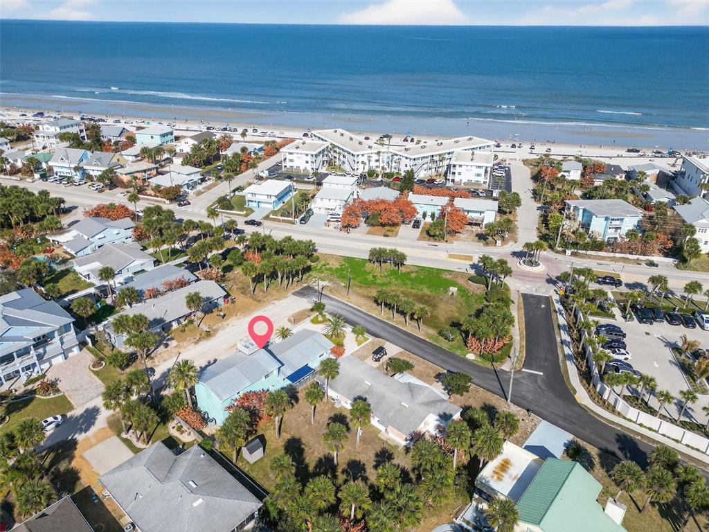 An aerial view shows a light blue house near a beach with palm trees — 923 LOCUST STREET, NEW SMYRNA BEACH, FL