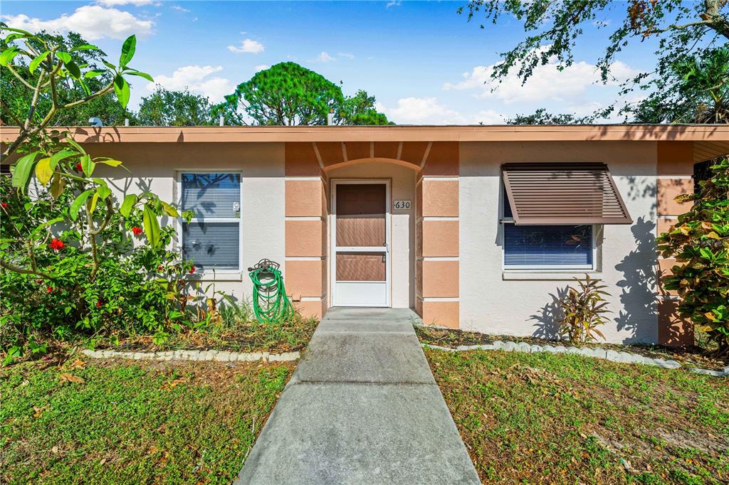A single-story house exterior features a concrete walkway leading to a front door with a screen — 630 N JEFFERSON AVENUE UNIT 19, SARASOTA, FL