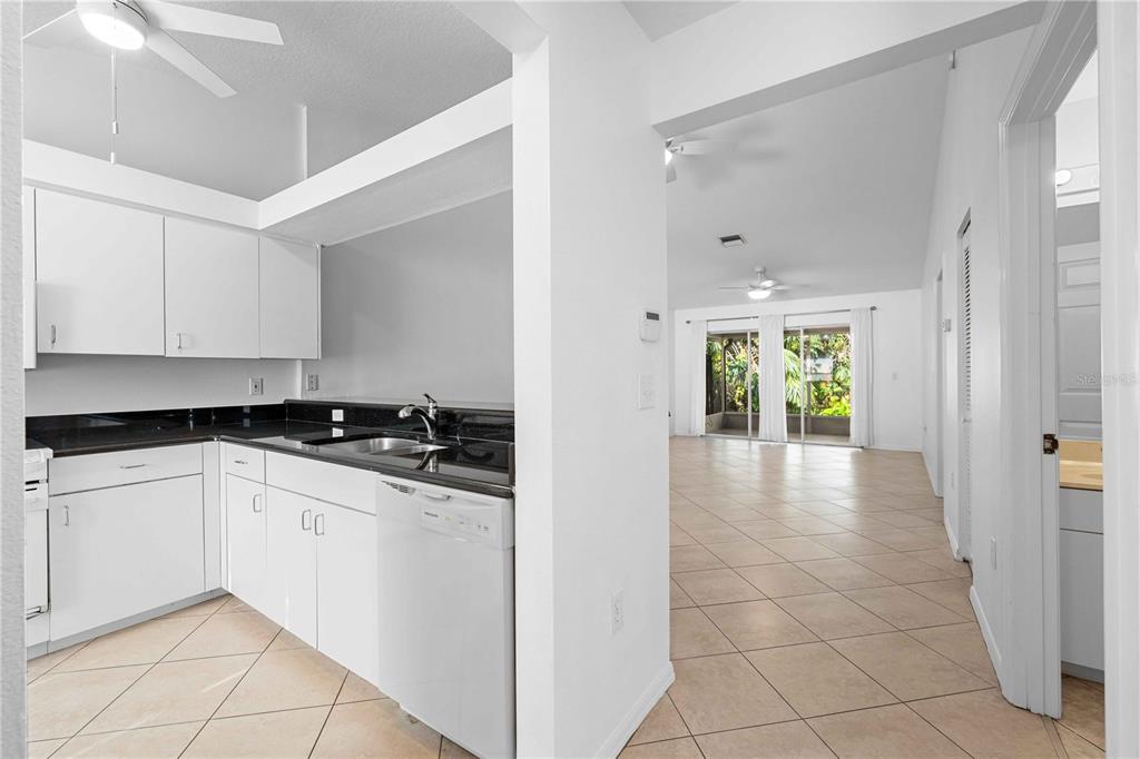 A kitchen with white cabinets and black countertops opens into a tiled living area — 630 N JEFFERSON AVENUE UNIT 19, SARASOTA, FL