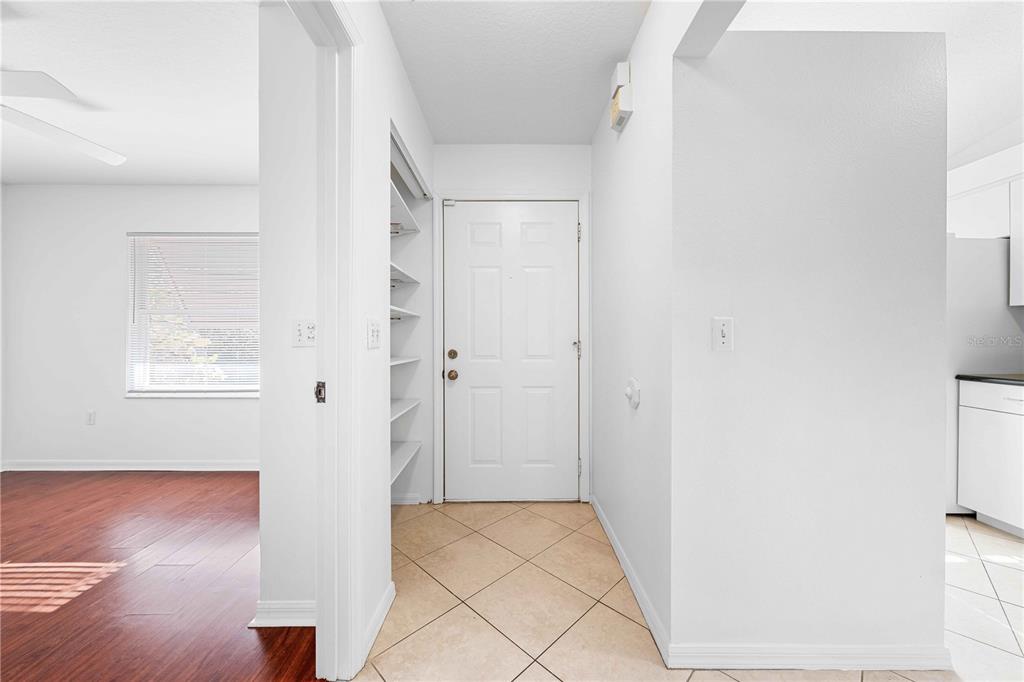 An entryway with tile flooring, a white door, and an adjacent open shelving closet — 630 N JEFFERSON AVENUE UNIT 19, SARASOTA, FL