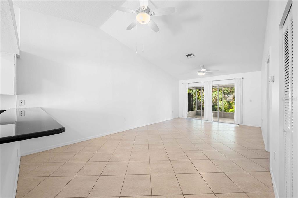 An open-concept living area with white walls, tile flooring, two ceiling fans, and sliding glass doors — 630 N JEFFERSON AVENUE UNIT 19, SARASOTA, FL