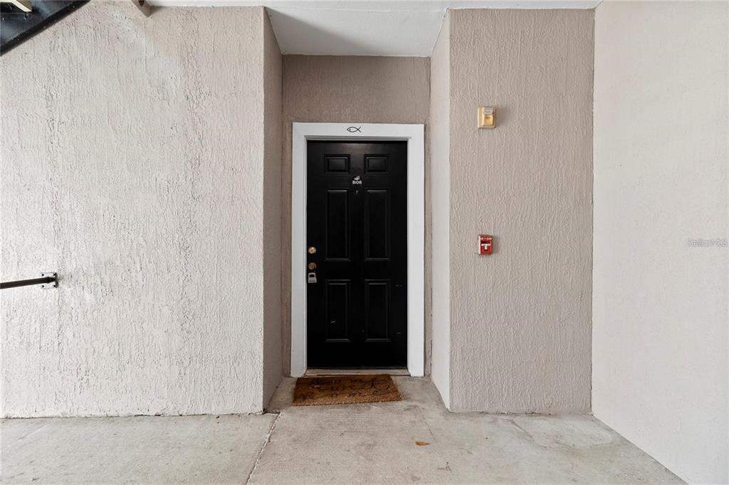 A black front door with a white frame is set into a textured beige wall — 3428 SOHO STREET UNIT B08, ORLANDO, FL