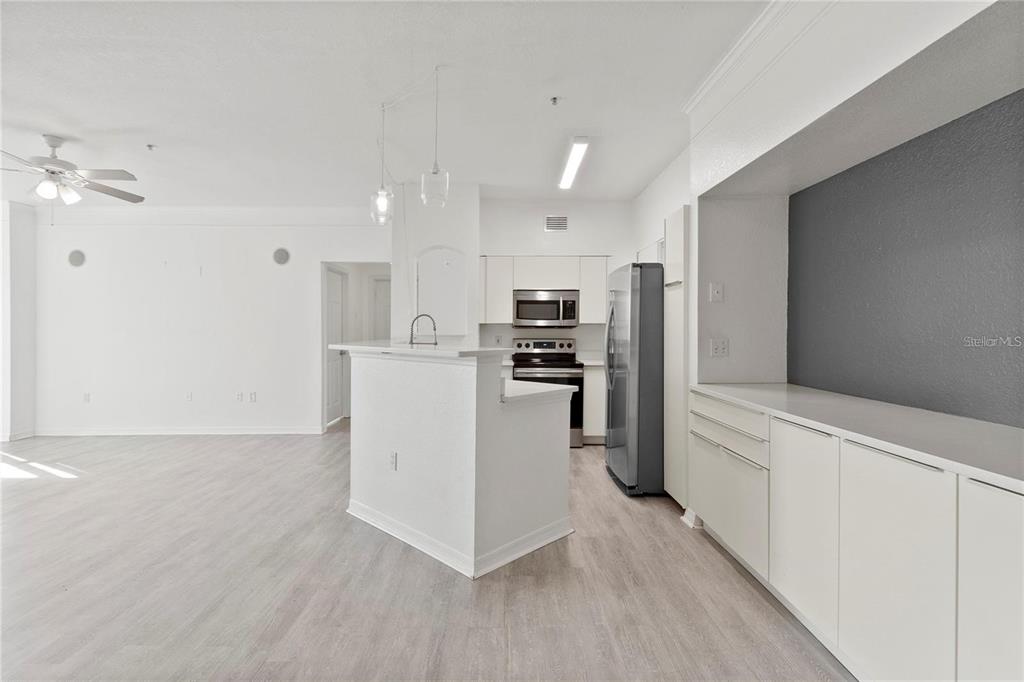 A kitchen with white cabinets, stainless steel appliances, and a breakfast bar island — 3428 SOHO STREET UNIT B08, ORLANDO, FL
