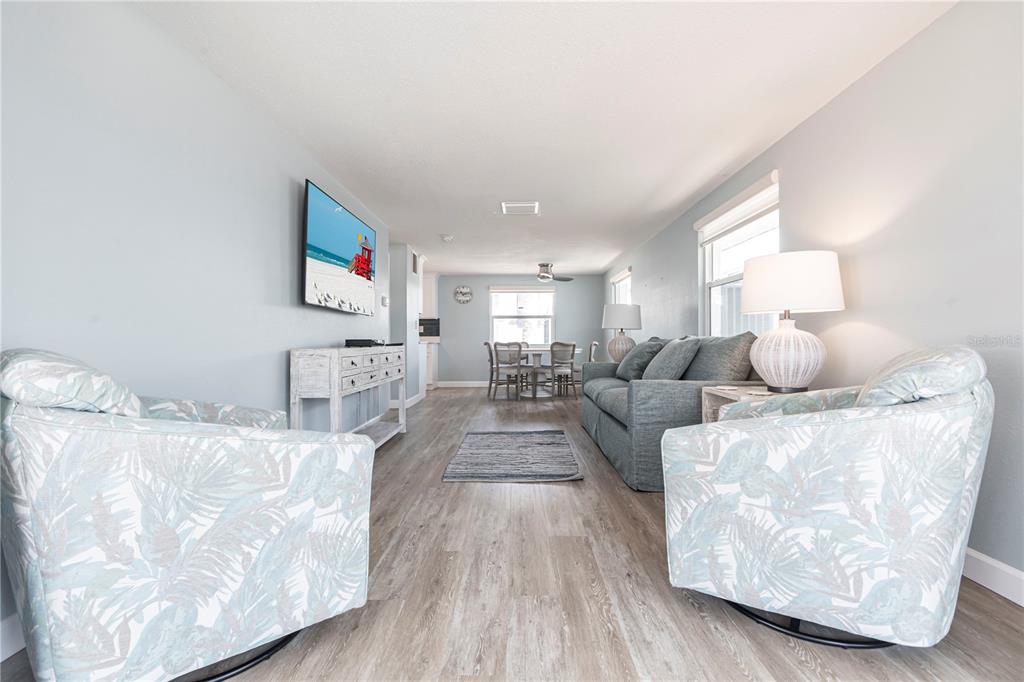 A living room features light blue walls, wood-look flooring, two patterned armchairs, and a sofa — 6020 MIDNIGHT PASS ROAD UNIT 53, SARASOTA, FL