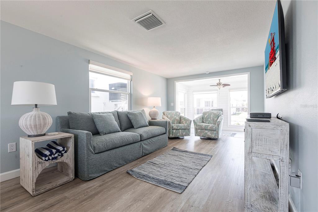 A living room features a blue sofa, two patterned armchairs, and light wood flooring — 6020 MIDNIGHT PASS ROAD UNIT 53, SARASOTA, FL