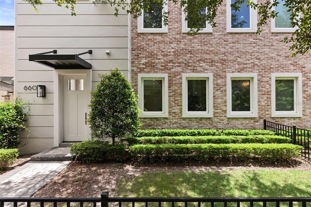 The exterior of a modern home features a brick facade, white door, and manicured hedges — 660 W MORSE BOULEVARD, WINTER PARK, FL