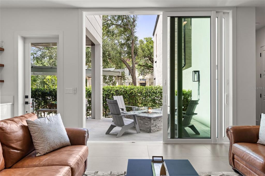 A living room with leather sofas opens through sliding glass doors to a patio with chairs — 660 W MORSE BOULEVARD, WINTER PARK, FL